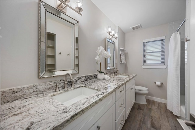 bathroom featuring hardwood / wood-style flooring, vanity, toilet, and walk in shower