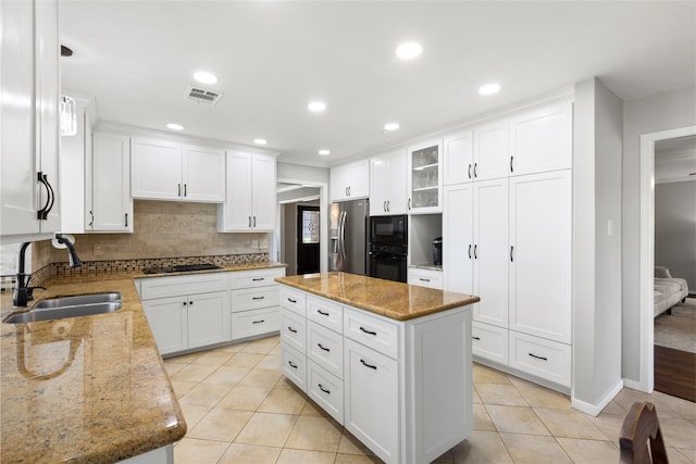 kitchen featuring a kitchen island, white cabinetry, sink, light stone counters, and black appliances