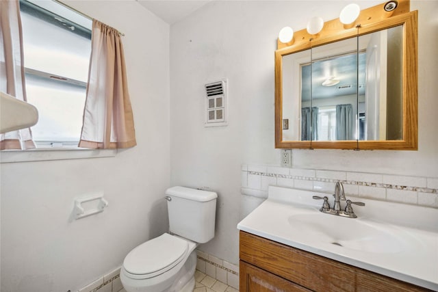 bathroom with tasteful backsplash, vanity, toilet, and a wealth of natural light