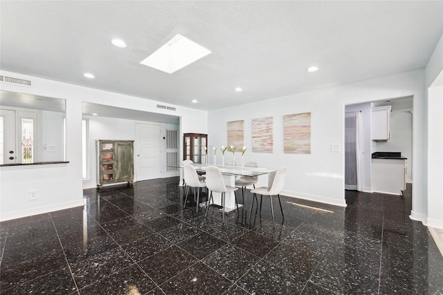 unfurnished dining area featuring a skylight and a textured ceiling