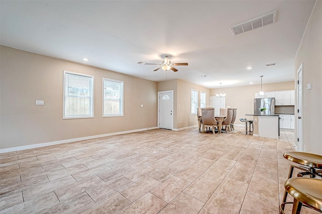 tiled living room featuring ceiling fan with notable chandelier