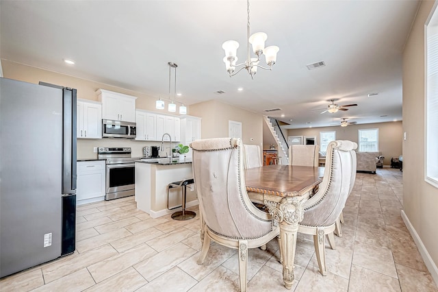 dining space with sink and ceiling fan with notable chandelier