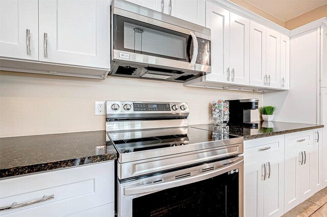 kitchen featuring white cabinetry, stainless steel appliances, and dark stone countertops