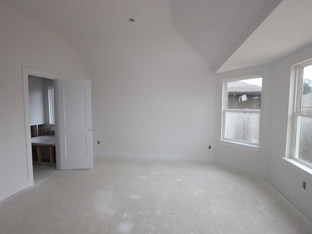 unfurnished room with unfinished concrete floors, baseboards, and lofted ceiling