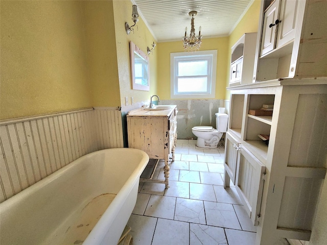 bathroom with a chandelier, vanity, a bathing tub, crown molding, and toilet