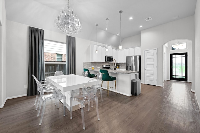 dining space featuring sink, dark hardwood / wood-style floors, high vaulted ceiling, and a notable chandelier