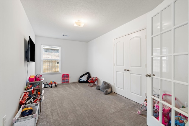 playroom with carpet floors and a textured ceiling