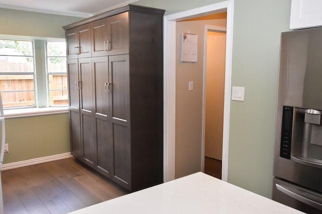 bedroom featuring dark wood-style flooring, crown molding, a closet, stainless steel fridge, and baseboards