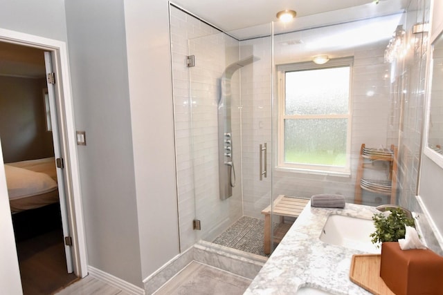 ensuite bathroom featuring a wealth of natural light, a stall shower, and a sink