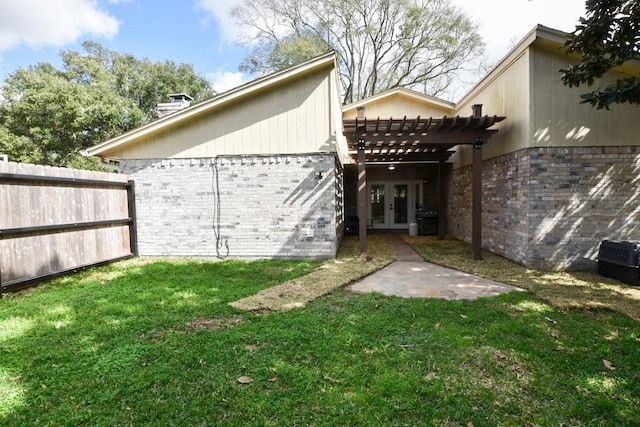 exterior space featuring brick siding, fence, french doors, a lawn, and a pergola