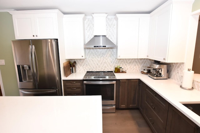 kitchen with white cabinetry, light countertops, appliances with stainless steel finishes, decorative backsplash, and wall chimney exhaust hood