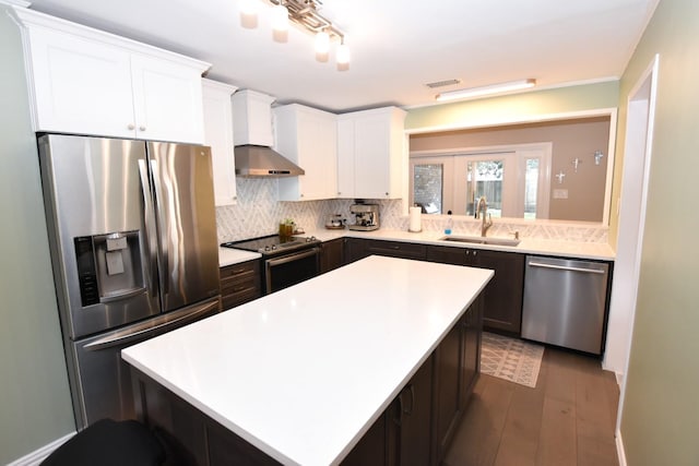 kitchen with stainless steel appliances, wall chimney range hood, a sink, and decorative backsplash