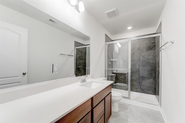 bathroom with a shower with door, vanity, tile patterned floors, and toilet