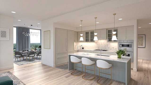 kitchen with gray cabinets, double oven, tasteful backsplash, light stone countertops, and light wood-type flooring