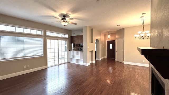 unfurnished living room with ceiling fan with notable chandelier, dark hardwood / wood-style floors, and a textured ceiling