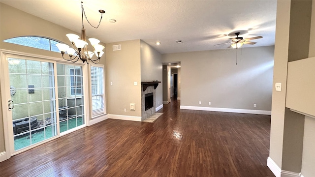 unfurnished living room featuring dark wood-type flooring, ceiling fan with notable chandelier, and a textured ceiling