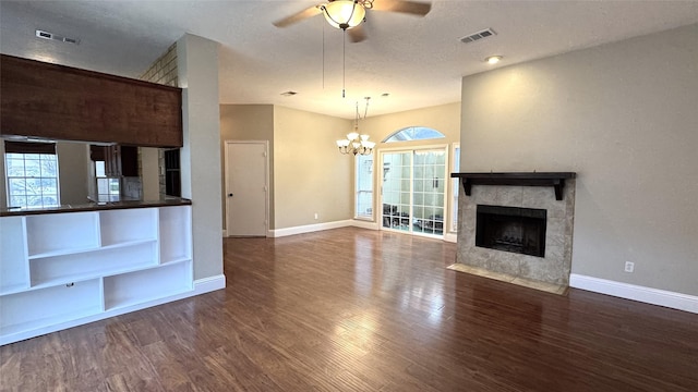 unfurnished living room featuring a wealth of natural light, ceiling fan with notable chandelier, and dark hardwood / wood-style flooring