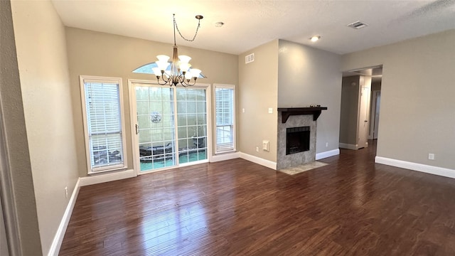 unfurnished living room featuring a notable chandelier, a tile fireplace, and dark hardwood / wood-style floors