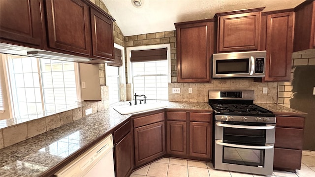 kitchen with tasteful backsplash, sink, light tile patterned floors, and appliances with stainless steel finishes