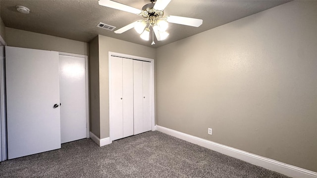 unfurnished bedroom with ceiling fan, a textured ceiling, a closet, and dark colored carpet