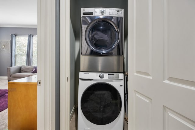 laundry area featuring crown molding and stacked washer and dryer