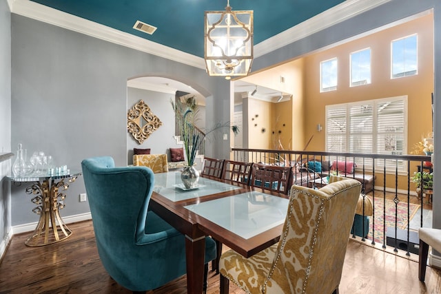 dining room with hardwood / wood-style flooring, crown molding, and an inviting chandelier