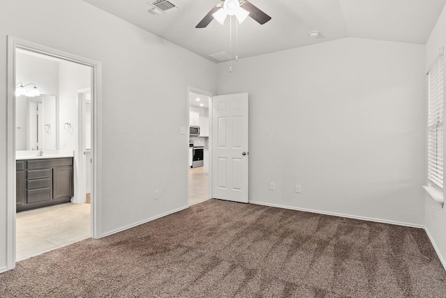 unfurnished bedroom featuring sink, ensuite bath, vaulted ceiling, and light colored carpet