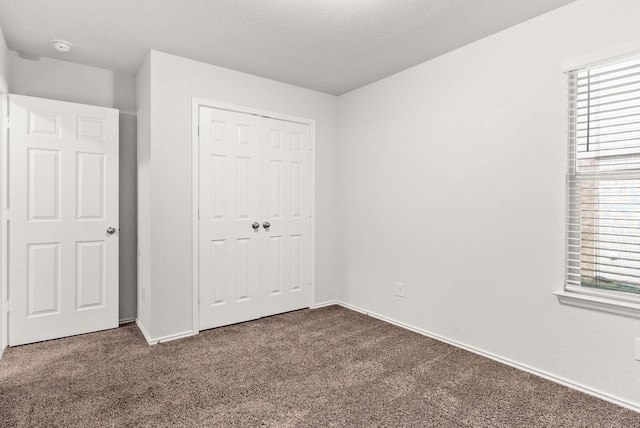 unfurnished bedroom featuring a closet, multiple windows, and dark colored carpet