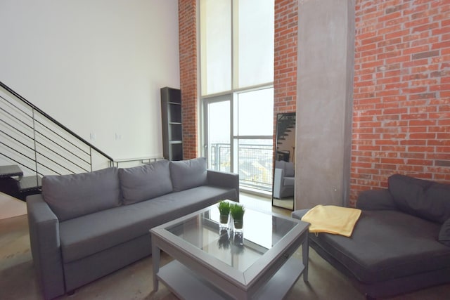 living room with brick wall, a towering ceiling, and a wall of windows