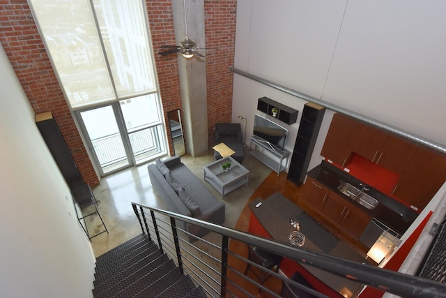 kitchen featuring ceiling fan, a towering ceiling, brick wall, and concrete flooring