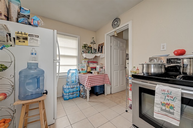 kitchen featuring white fridge, light tile patterned floors, and electric range