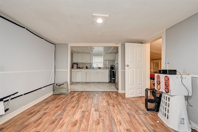 living room with sink, a textured ceiling, and light wood-type flooring