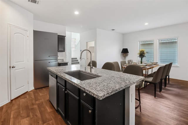 kitchen featuring a kitchen bar, sink, appliances with stainless steel finishes, dark hardwood / wood-style floors, and an island with sink