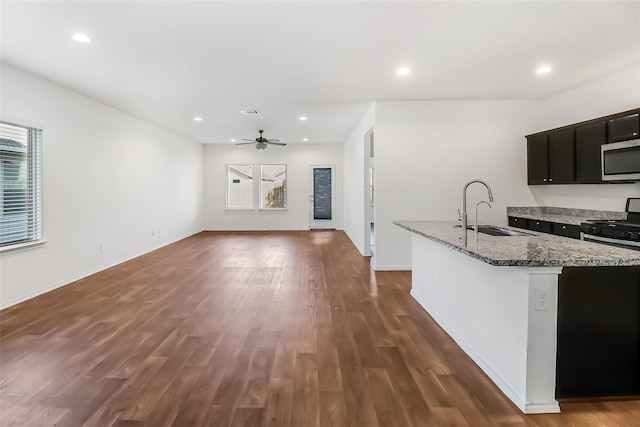 kitchen with dark hardwood / wood-style floors, sink, a kitchen island with sink, ceiling fan, and light stone counters