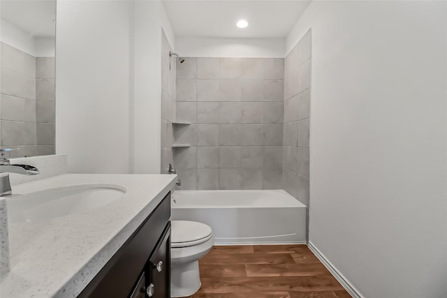 full bathroom featuring wood-type flooring, toilet, tiled shower / bath combo, and vanity