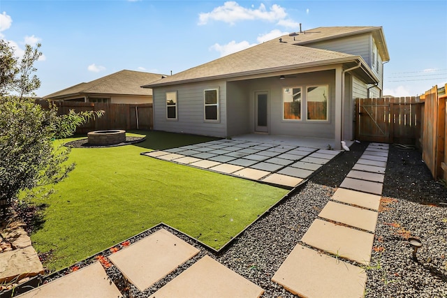 back of property with a yard, a fire pit, and a patio area