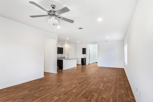 unfurnished living room with ceiling fan, sink, and dark hardwood / wood-style flooring