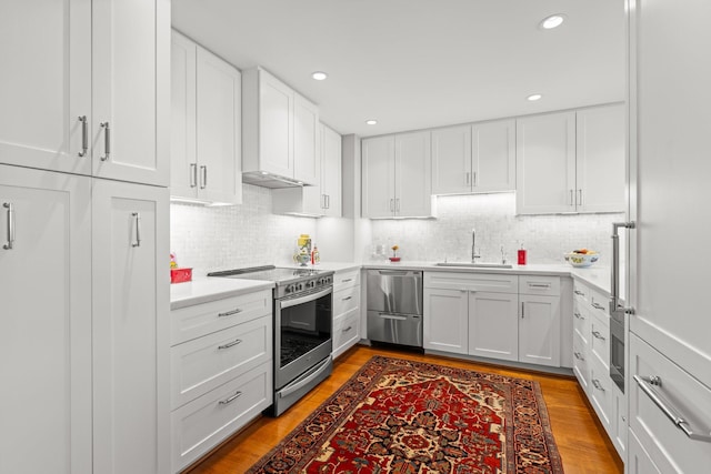 kitchen with stainless steel appliances, sink, white cabinets, and light wood-type flooring