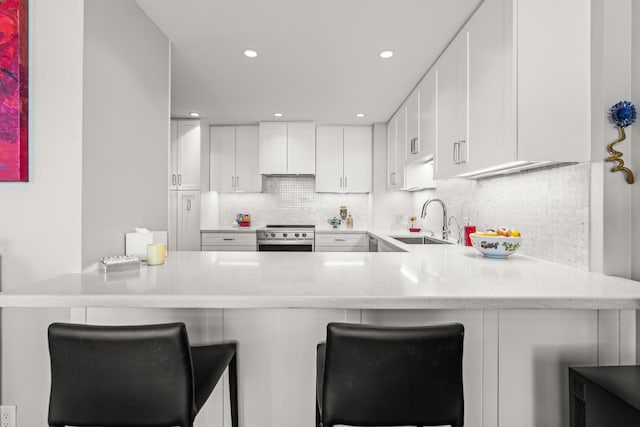 kitchen with sink, a breakfast bar area, white cabinets, and kitchen peninsula