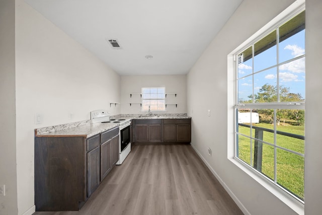 kitchen featuring sink, electric range, dark brown cabinets, light hardwood / wood-style floors, and light stone countertops