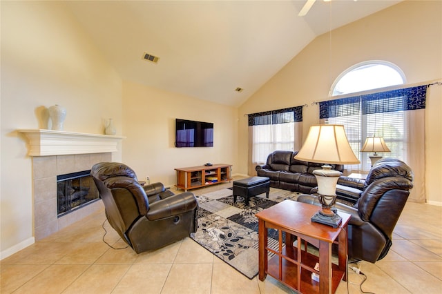 living room with visible vents, high vaulted ceiling, a tiled fireplace, and light tile patterned flooring