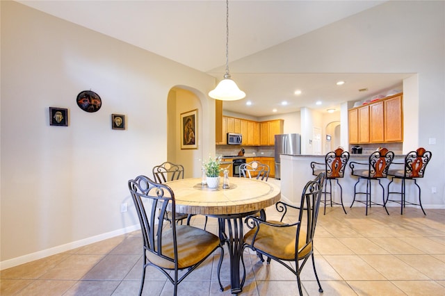 dining space with arched walkways, light tile patterned floors, recessed lighting, vaulted ceiling, and baseboards