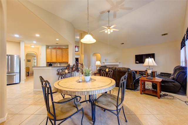 dining space featuring arched walkways, light tile patterned floors, lofted ceiling, visible vents, and a ceiling fan