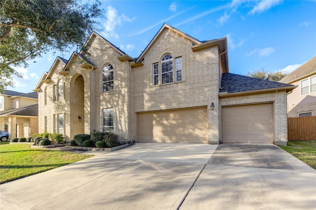 traditional-style home featuring concrete driveway, brick siding, a front lawn, and an attached garage