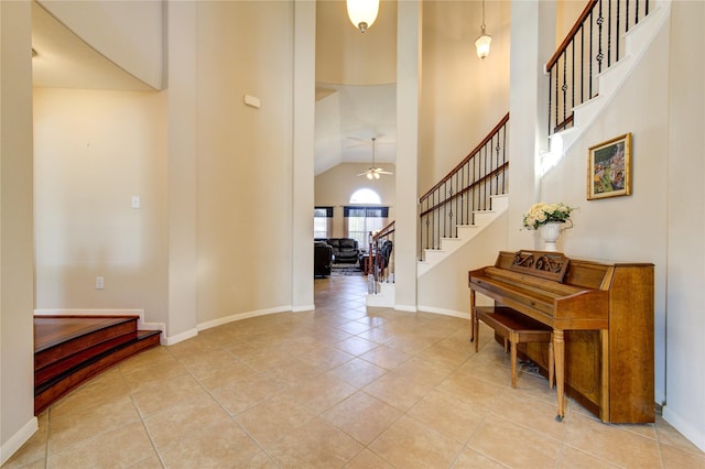 foyer with light tile patterned floors, stairway, a ceiling fan, high vaulted ceiling, and baseboards