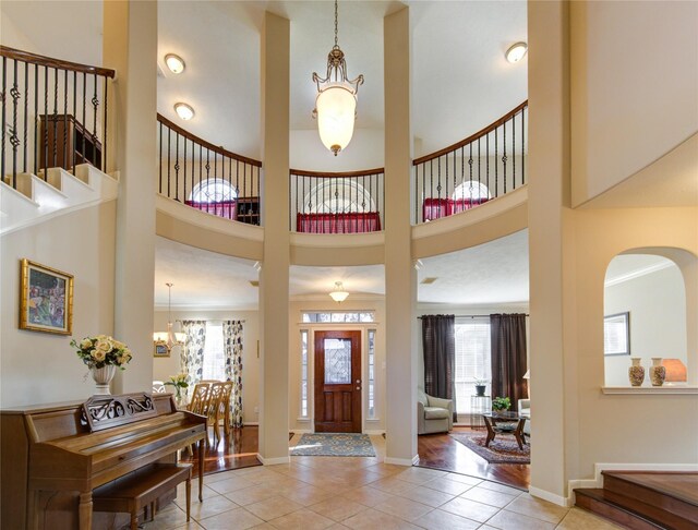 foyer featuring baseboards, stairs, a high ceiling, a notable chandelier, and light tile patterned flooring