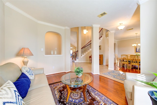 living room featuring crown molding, visible vents, stairway, wood finished floors, and a chandelier