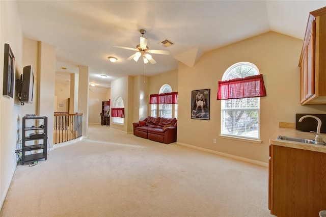 sitting room with baseboards, vaulted ceiling, visible vents, and light colored carpet