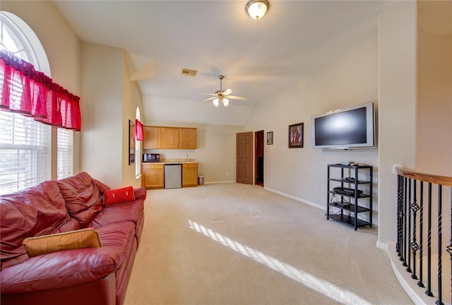 living room with light carpet, visible vents, baseboards, ceiling fan, and vaulted ceiling