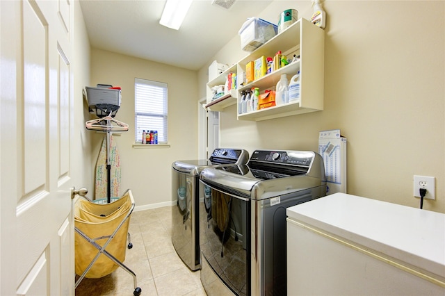 clothes washing area featuring laundry area, light tile patterned floors, baseboards, and separate washer and dryer